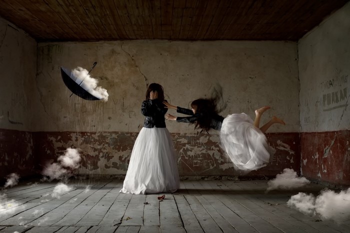 Two women in a room with an umbrella and clouds