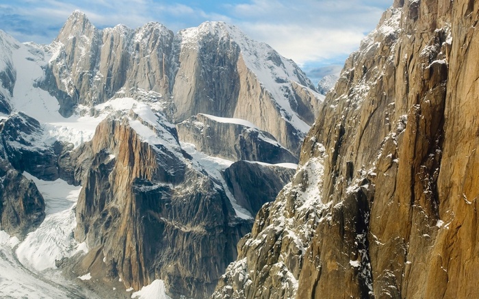 Snow-covered rocky mountains under a cloudy sky