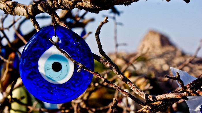 Blue evil eye charm hanging on a tree branch