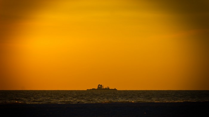 Ship on the horizon at sunset over the ocean
