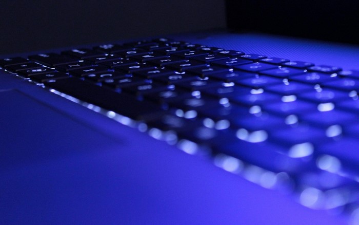 Close-up of a backlit laptop keyboard with blue lighting