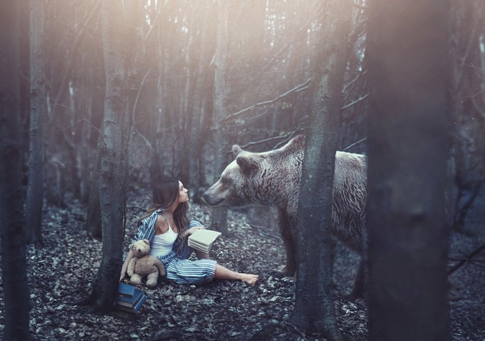 Girl reading with a bear in a forest