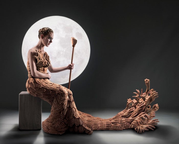 Sculpture of a woman in a dress made of hands with a moon background