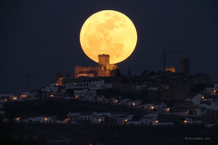 Full moon over a castle and town at night