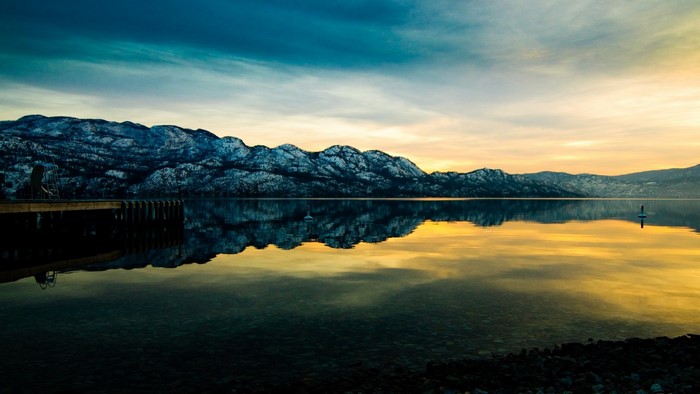 Snow-capped mountains reflected in a lake at sunset