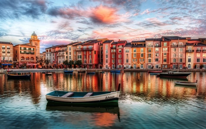 Colorful buildings reflected in a canal with boats at dusk