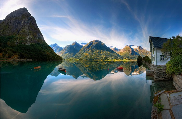 Calm lake reflecting mountains and a house