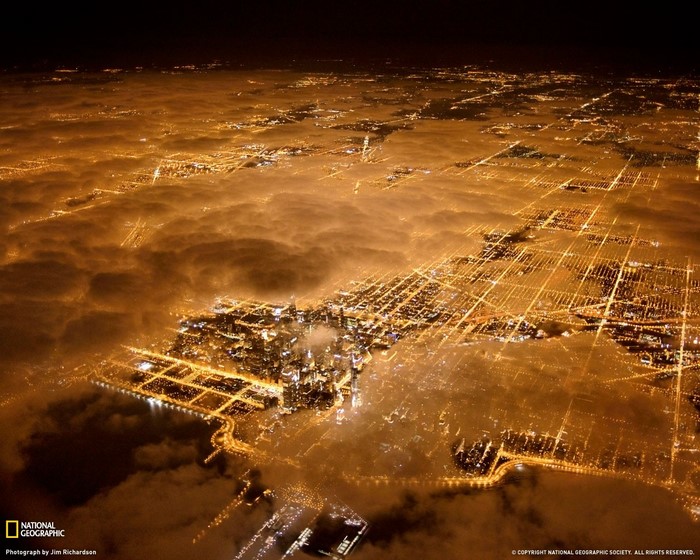 Aerial view of Chicago cityscape at night through clouds