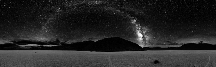 Milky Way over a desert landscape with mountains and a car
