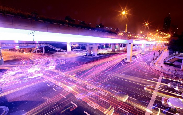 Cityscape at night with light trails from traffic on an interchange