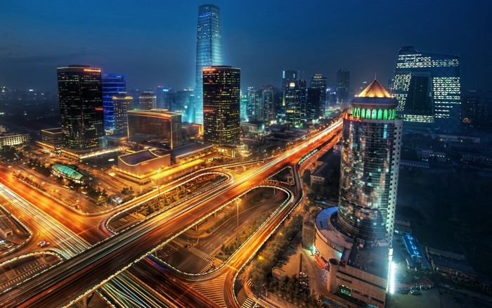 Cityscape at night with illuminated skyscrapers and highway interchange