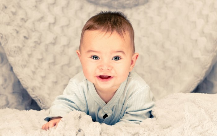Baby with blue eyes lying on a fluffy blanket