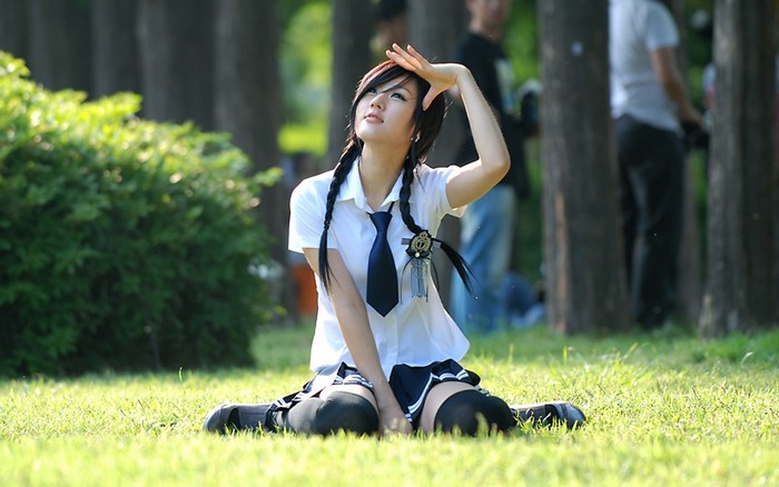 Young woman in school uniform sitting on grass