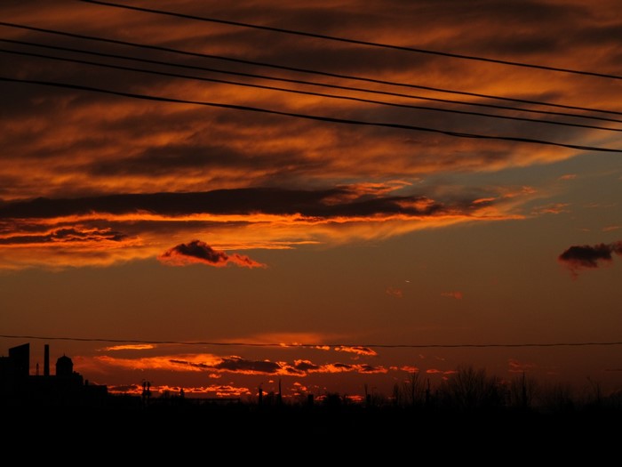 Sunset with clouds and power lines over silhouette