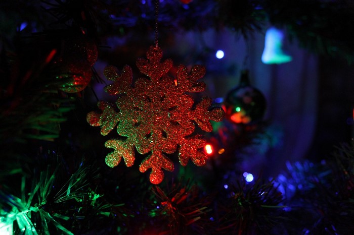 Glittering snowflake ornament on a Christmas tree with lights