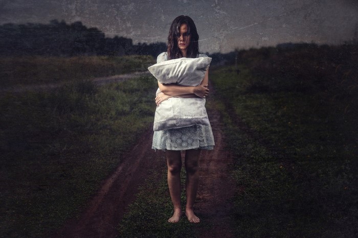 Woman holding a pillow on a dirt path