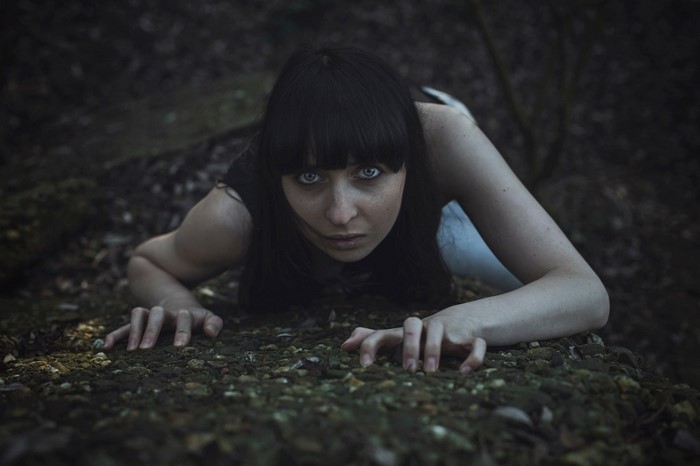 Woman crawling on the ground in the dark