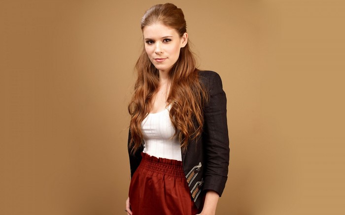 Kate Mara in a black jacket and red skirt