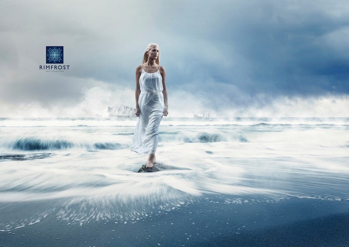 Woman in white dress on a rocky shore with waves
