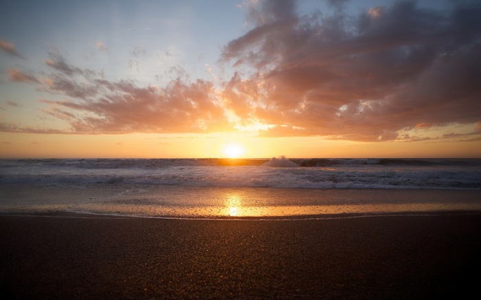 Sunset over the ocean with waves and clouds