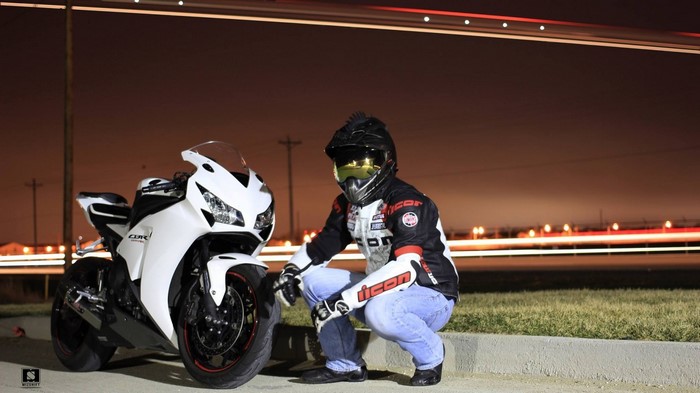 Man in motorcycle gear with Honda CBR motorcycle at night