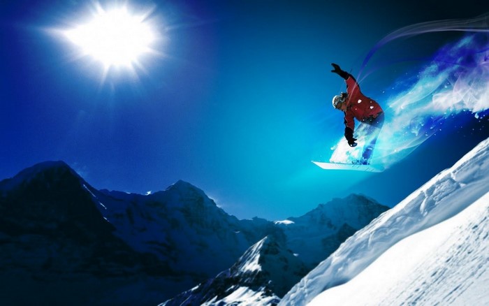 Snowboarder jumping over snowy mountains under the sun