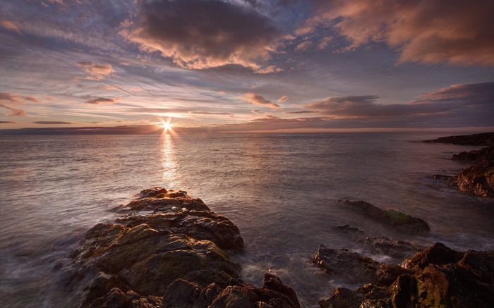 Sunset over the ocean with rocky shore