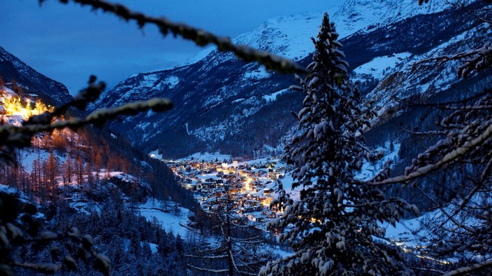 Village nestled in snowy mountains at dusk
