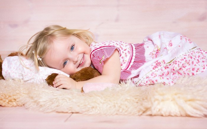 Smiling Toddler Girl Lying on Soft Rug
