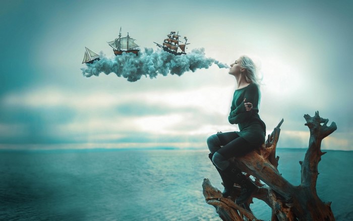 Woman exhaling clouds with ships on them over the ocean