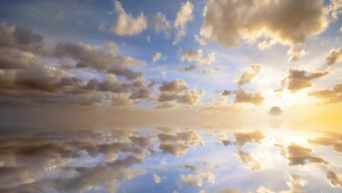 Sky with clouds reflected in water at sunset