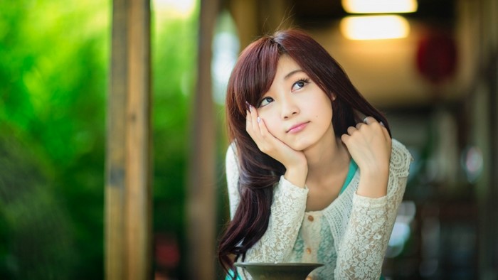 Young Asian woman with long brown hair looking away