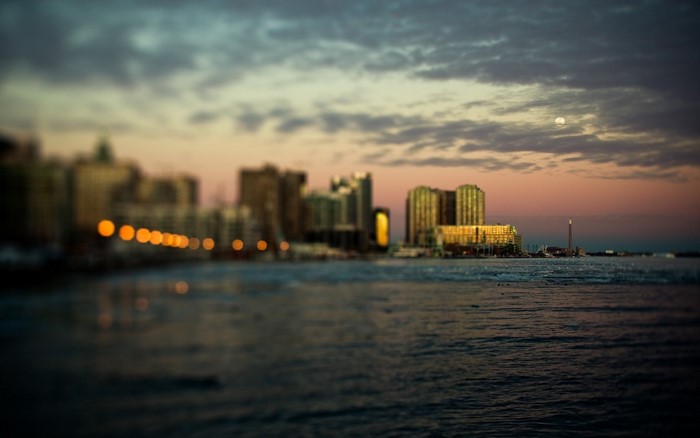 Cityscape at sunset with moon over the water