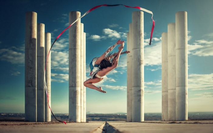 Woman performing rhythmic gymnastics with ribbon near pillars