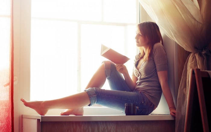 Woman reading a book by the window