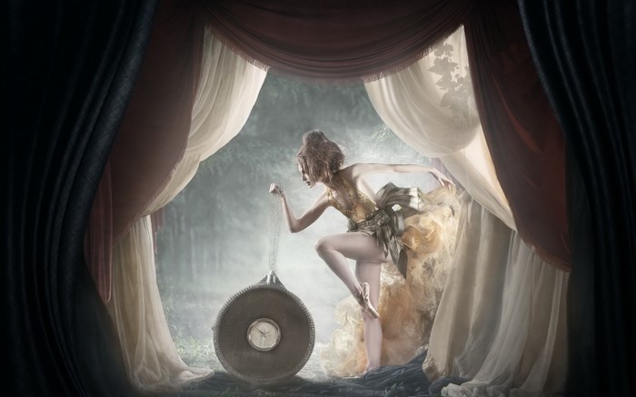 Woman pouring sand from hourglass in a mystical forest
