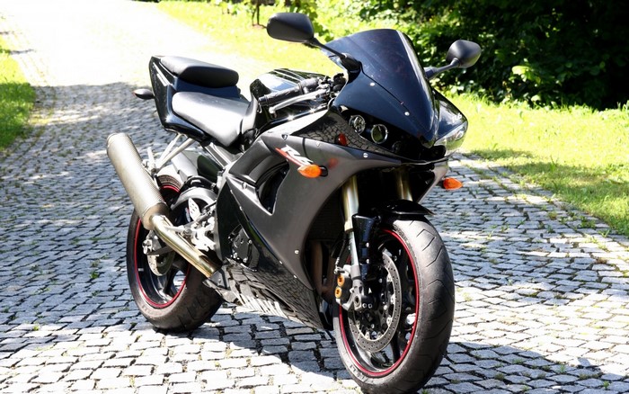 Black Yamaha R6 motorcycle parked on cobblestone path