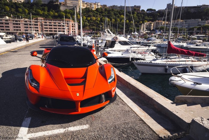 Orange Ferrari LaFerrari parked by a marina with yachts