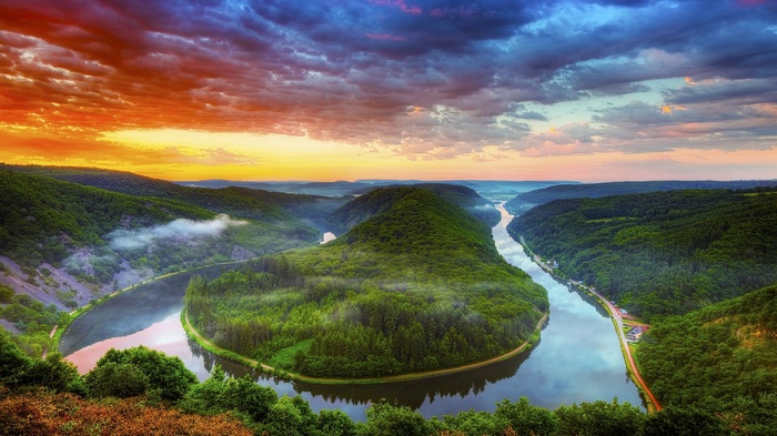 Meandering river through green hills at sunset