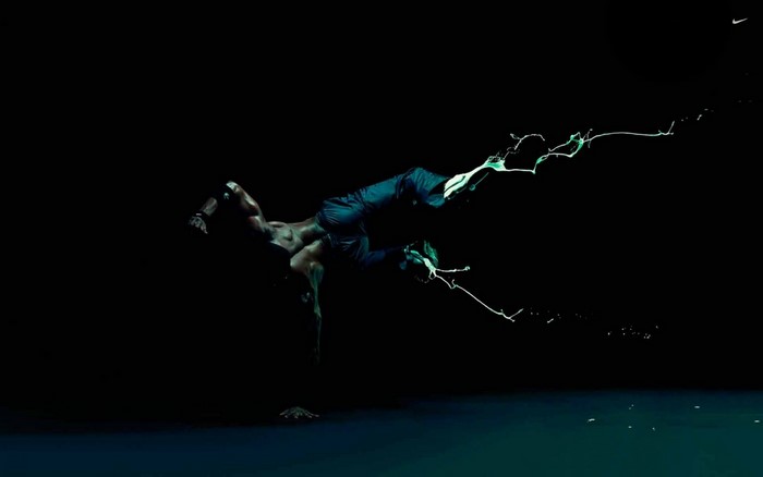 Man performing a breakdance move with green liquid splashes