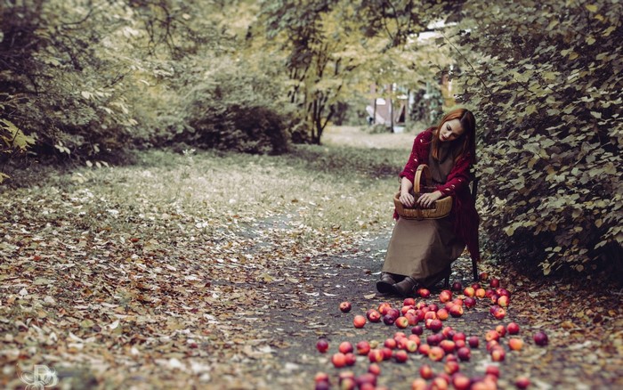 Woman with basket and apples in autumn forest