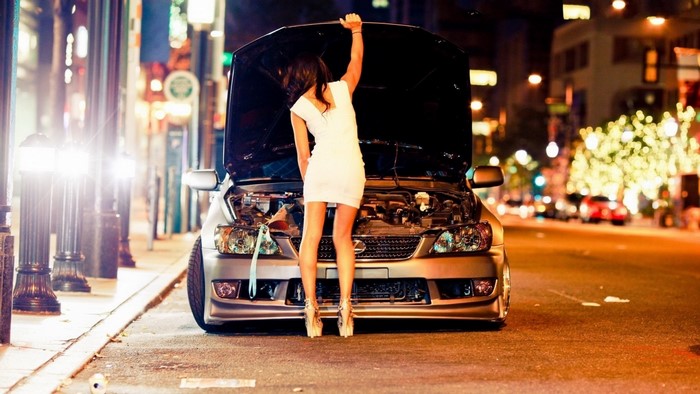 Woman in white dress with car hood open at night