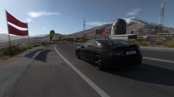 Black Audi RS5 driving on a race track with flags