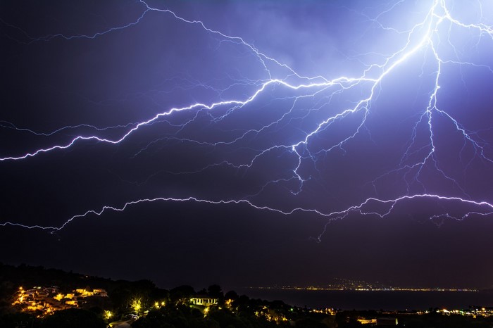 Lightning strikes over a coastal town at night