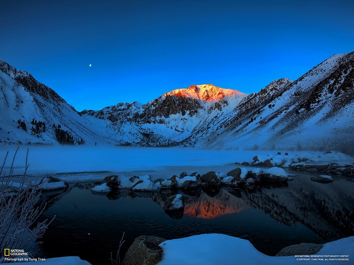 Snowy mountains reflecting in a lake at dawn