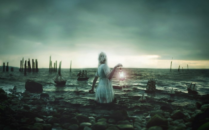 Woman with lantern in the sea with ships