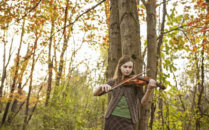 Girl playing violin in autumn forest