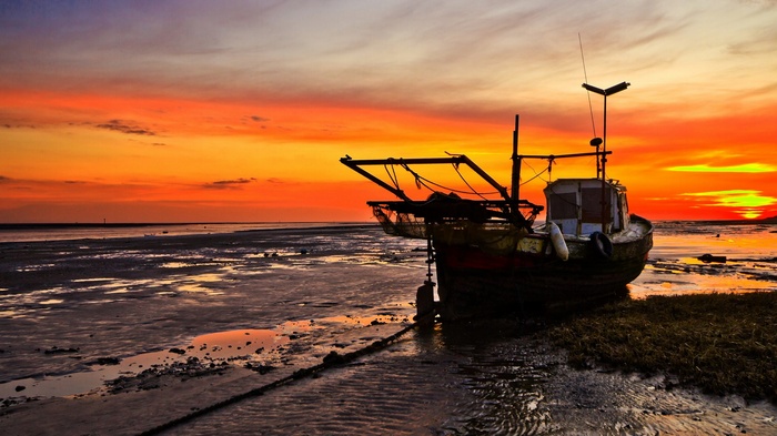Fishing boat on a beach at sunset