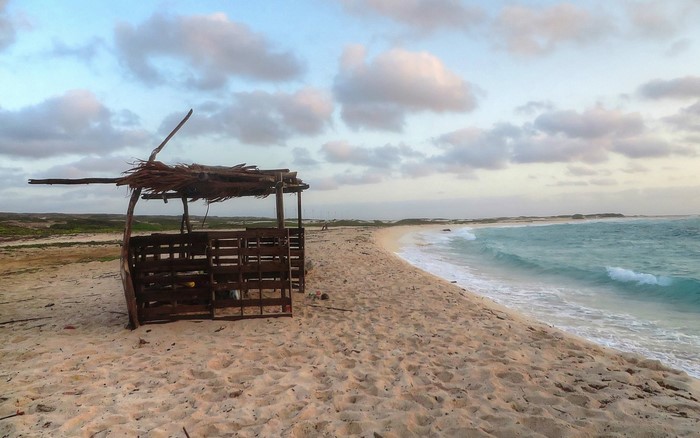 Beach hut on a sandy shore with turquoise ocean waves