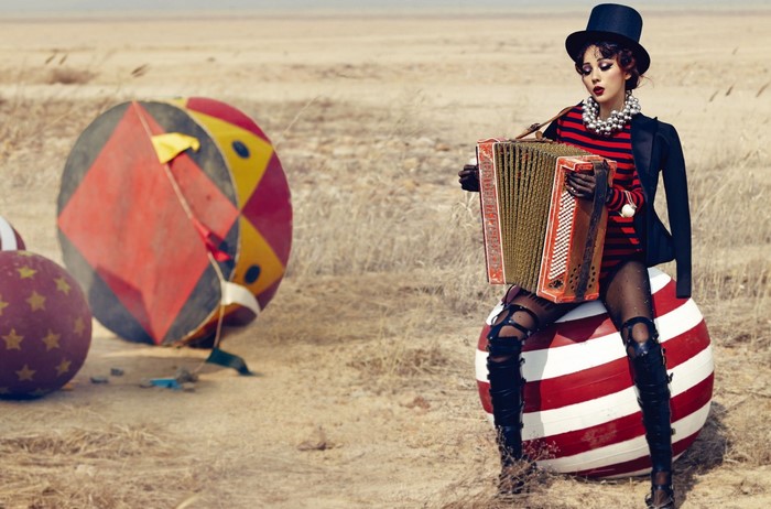 Woman in circus attire playing accordion in a desert